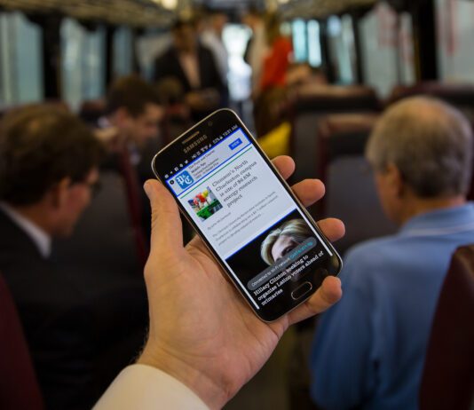 Here’s How to Get Free Wifi on Brighton’s Buses Person Using Phone on Bus