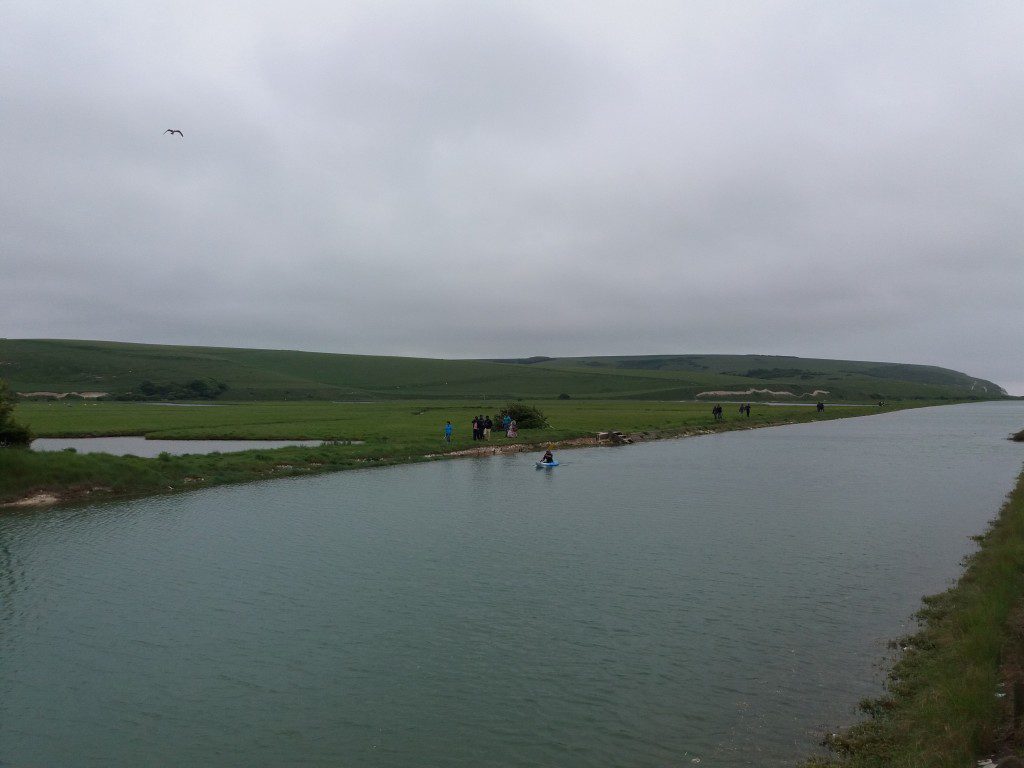 Walk through the grasslands along the little river, watching people canoeing.